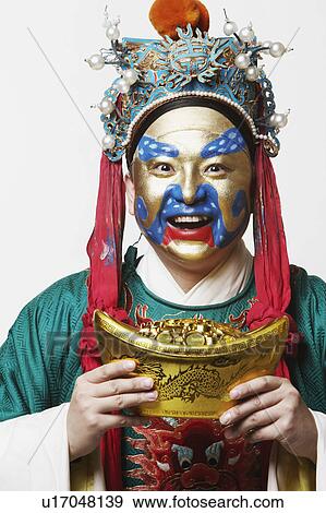 Stock Photo - Portrait of a male Chinese opera performer holding a bowl full of gold coins. Fotosearch