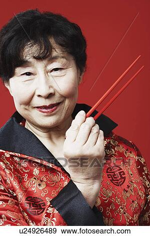 Stock Photo - Portrait of a mature woman holding chopsticks. Fotosearch