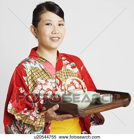 Portrait of a young woman holding tea cups and a tea kettle on a tray View Large Photo Image Stock Photography - Portrait of a young woman holding tea cups and a tea kettle on a tray. Fotosearch
