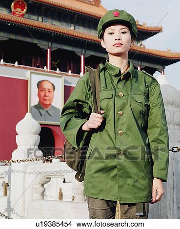 Picture - Portrait of a young woman in army uniform standing in front of a palace, Forbidden Palace, Beijing, China. Fotosearch