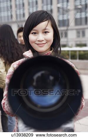 Stock Photo - Close-up of a telescope in front of a young woman. Fotosearch