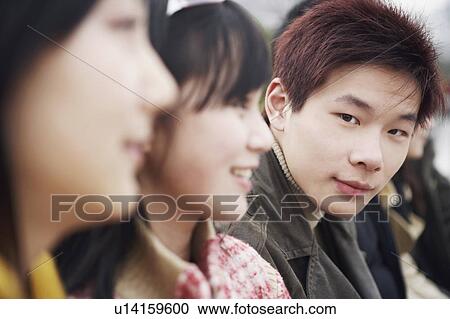 Stock Image - Close-up of a young man with two young women. Fotosearch