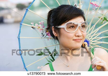 Stock Image - Close-up of a young woman holding a parasol. Fotosearch