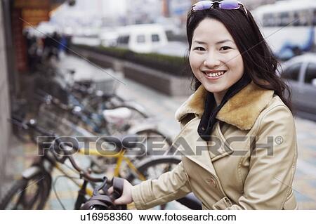 Close-up of a young woman holding a bicycle View Large Photo Image Stock Image - Close-up of a young woman holding a bicycle. Fotosearch