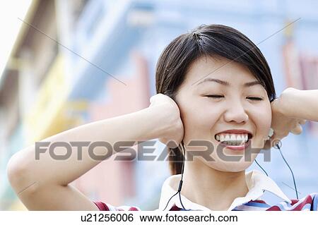 Stock Photograph - Close-up of a young woman listening to music. Fotosearch
