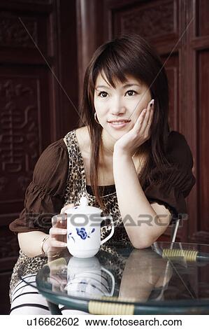Stock Image - Close-up of a young woman smiling with her hand under her chin. Fotosearch