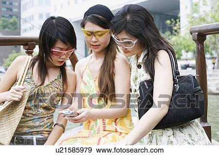 Close-up of three young women looking at a mobile phone View Large Photo Image Stock Photo - Close-up of three young women looking at a mobile phone. Fotosearch