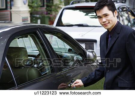 Stock Image - Portrait of a businessman unlocking a car door. Fotosearch