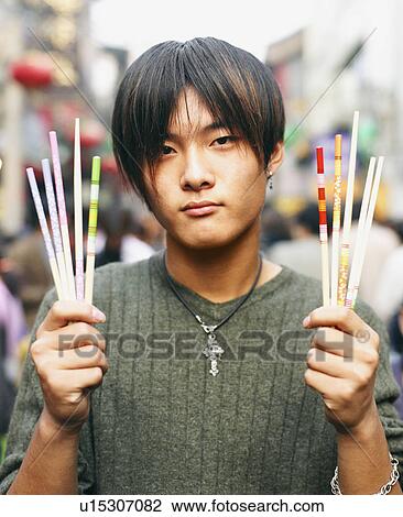 Stock Image - Portrait of a young man holding pencils and brushes. Fotosearch