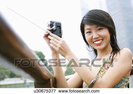 Stock Photo - Portrait of a young woman holding a home video camera. Fotosearch