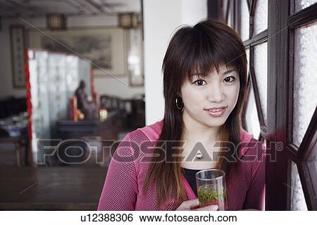 Stock Photograph - Portrait of a young woman holding a glass of herbal drink. Fotosearch