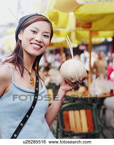 Stock Photograph - Portrait of a young woman holding a coconut drink. Fotosearch