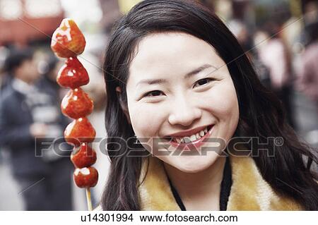 Picture - Portrait of a young woman smiling behind a stick of avocados. Fotosearch