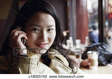 Stock Image - Portrait of a young woman using a mobile phone. Fotosearch