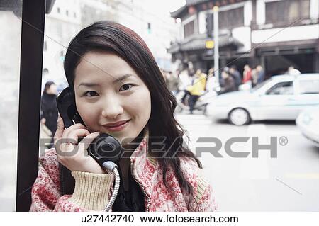 Stock Image - Portrait of a young woman using a telephone. Fotosearch