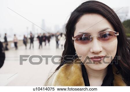 Stock Photography - Portrait of a young woman wearing sunglasses smiling. Fotosearch