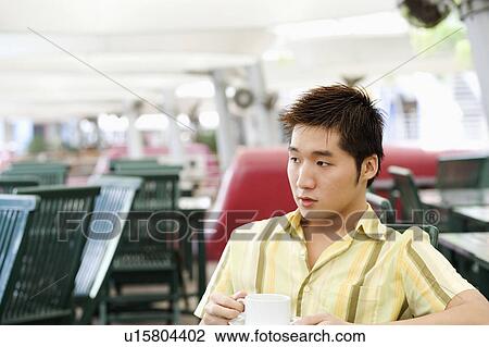 Young man holding a cup of coffee View Large Photo Image Stock Image - Young man holding a cup of coffee. Fotosearch