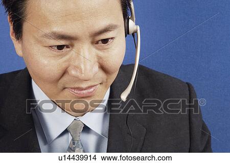 Picture - Close-up of a businessman wearing headsets. Fotosearch