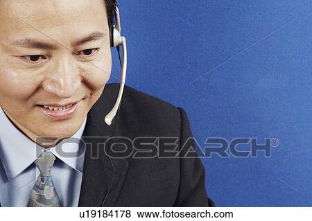 Stock Photo - Close-up of a businessman wearing headsets. Fotosearch