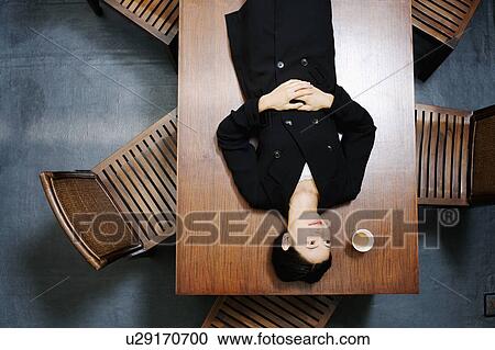 Stock Image - High angle view of a businesswoman lying on the table. Fotosearch