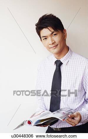 Stock Photograph - Portrait of a businessman holding a magazine and smirking. Fotosearch