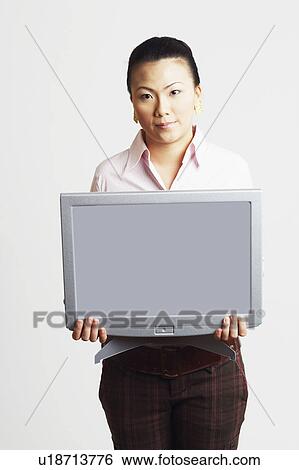 Stock Photograph - Portrait of a businesswoman holding the model of a computer monitor with progress reports. Fotosearch