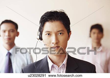 Stock Image - Portrait of a male customer service representative with two colleagues. Fotosearch