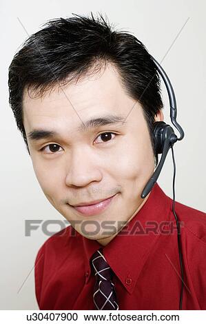 Stock Image - Portrait of a male customer service representative using a headset. Fotosearch