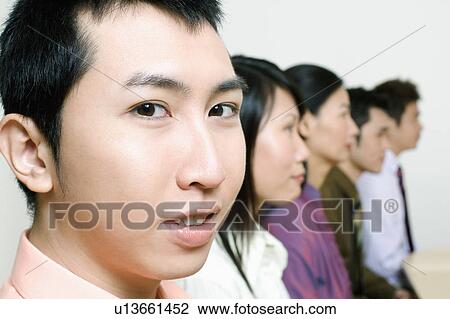 Stock Image - Three businessmen and two businesswomen sitting side by side. Fotosearch