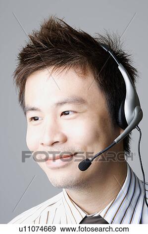 Stock Photo - Close-up of a businessman using a headset and smiling. Fotosearch