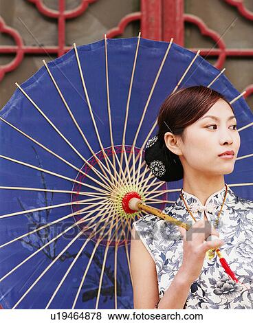 Stock Photo - Close-up of a young woman holding a parasol and looking sideways. Fotosearch