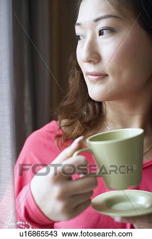Stock Image - Close-up of a young woman holding a tea cup. Fotosearch