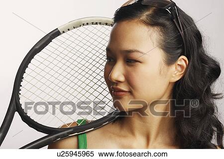 Close-up of a young woman looking away and holding a tennis racket View Large Photo Image Stock Photography - Close-up of a young woman looking away and holding a tennis racket. Fotosearch