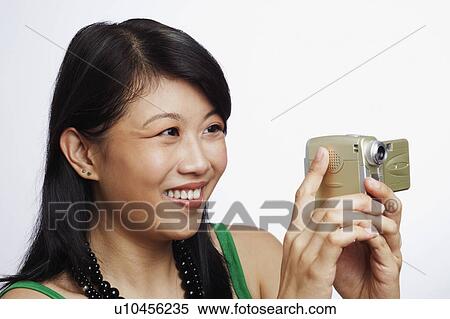 Stock Photography - Close-up of a young woman taking a photograph. Fotosearch