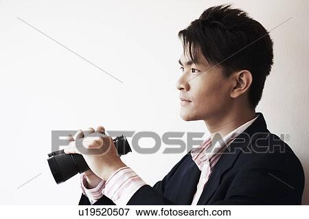 Stock Photo - Side profile of a businessman holding a pair of binoculars. Fotosearch