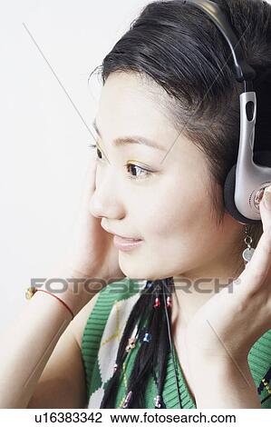 Stock Image - Side profile of a young woman listening to music. Fotosearch