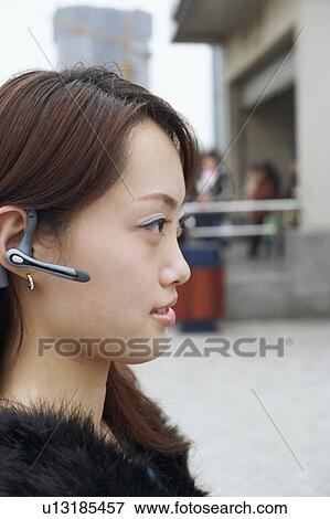 Side profile of a young woman wearing a hands free device View Large Photo Image Stock Photo - Side profile of a young woman wearing a hands free device. Fotosearch