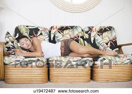 Stock Photo - A young woman sleeping on couch. Fotosearch