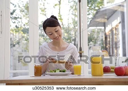 Stock Image - View of a young woman having breakfast. Fotosearch