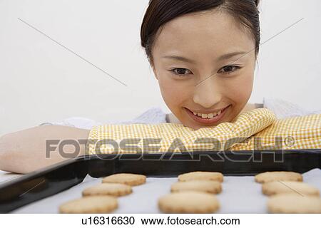 View of a young woman looking at a tray of biscuits View Large Photo Image Stock Image - View of a young woman looking at a tray of biscuits. Fotosearch