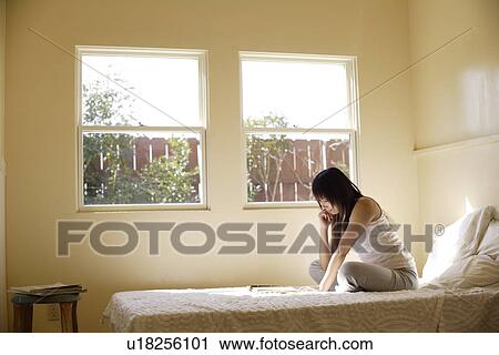 Young woman sitting on bed and reading View Large Photo Image Stock Image - Young woman sitting on bed and reading. Fotosearch