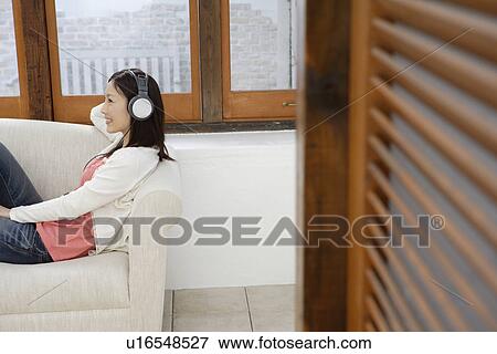 Stock Photo - A young woman using headphone. Fotosearch