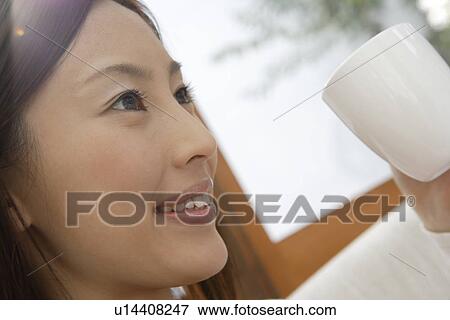 Stock Photo - Close-up of a cheerful young woman holding a cup. Fotosearch