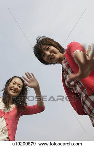 Low angle view of two young women showing their palms over the camera View Large Photo Image Stock Photo - Low angle view of two young women showing their palms over the camera. Fotosearch