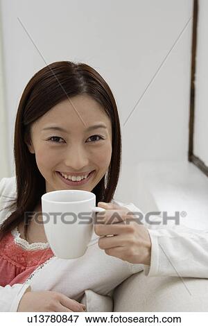 Stock Photo - Portrait of a cheerful young woman holding a cup. Fotosearch