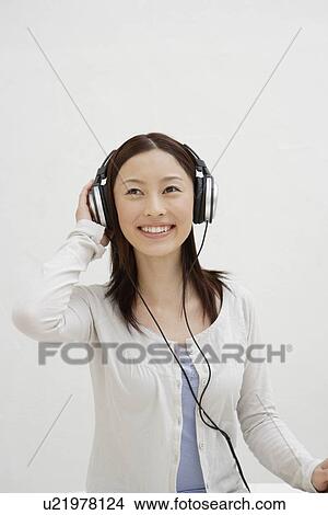 Picture - View of a cheerful woman using headphone. Fotosearch