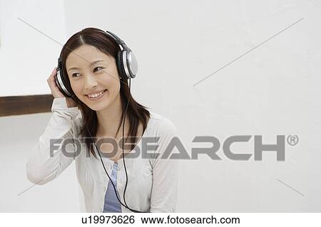 Stock Photograph - View of a cheerful woman using headphone. Fotosearch