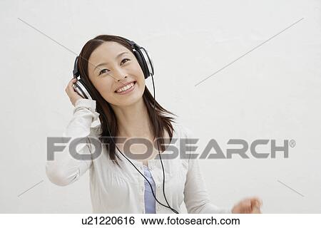 Stock Photograph - View of a cheerful woman using headphone. Fotosearch