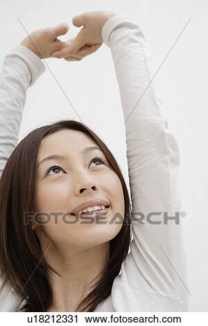 Stock Image - View of a cheerful woman with arms raised. Fotosearch