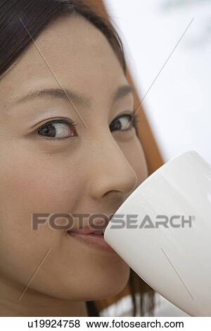 Stock Photo - View of a young woman having beverage. Fotosearch